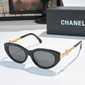 Black cat-eye sunglasses with dark lenses and gold chain detail on the temples.