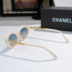 White cat-eye sunglasses with blue lenses and gold chain detail on the temples.
