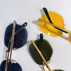 Assorted sunglasses with gold frames in blue, yellow, and green lenses.