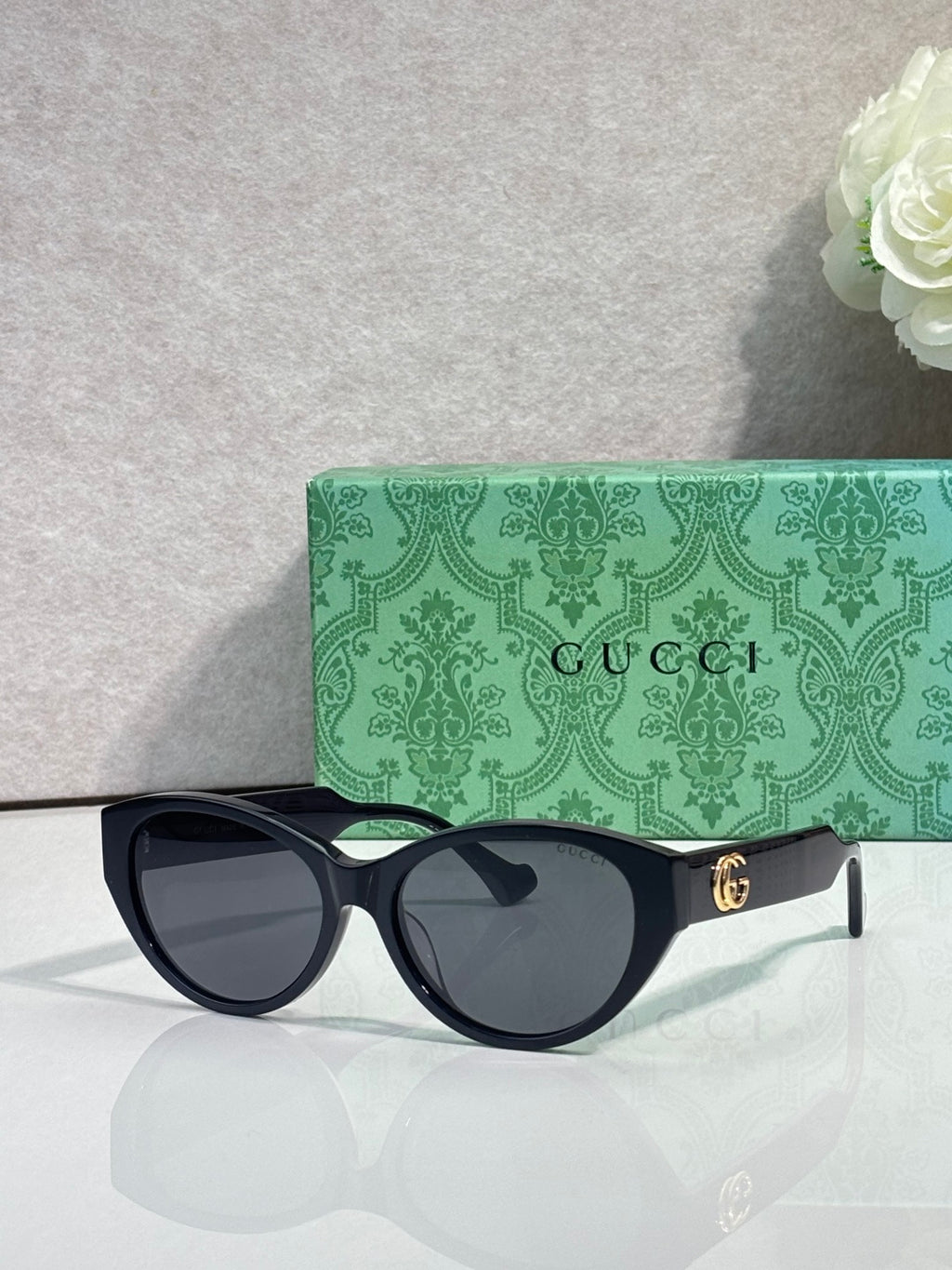 Gucci eyeglasses with black frame and dark lenses, gold emblem at temple.