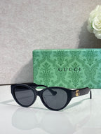 Gucci eyeglasses with black frame and dark lenses, gold emblem at temple.