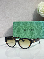 Gucci eyeglasses with dark tortoise frame and round lenses, gold logo detail.