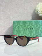 Gucci eyeglasses with dark tortoise frame and gold emblem on temple, tinted lenses.