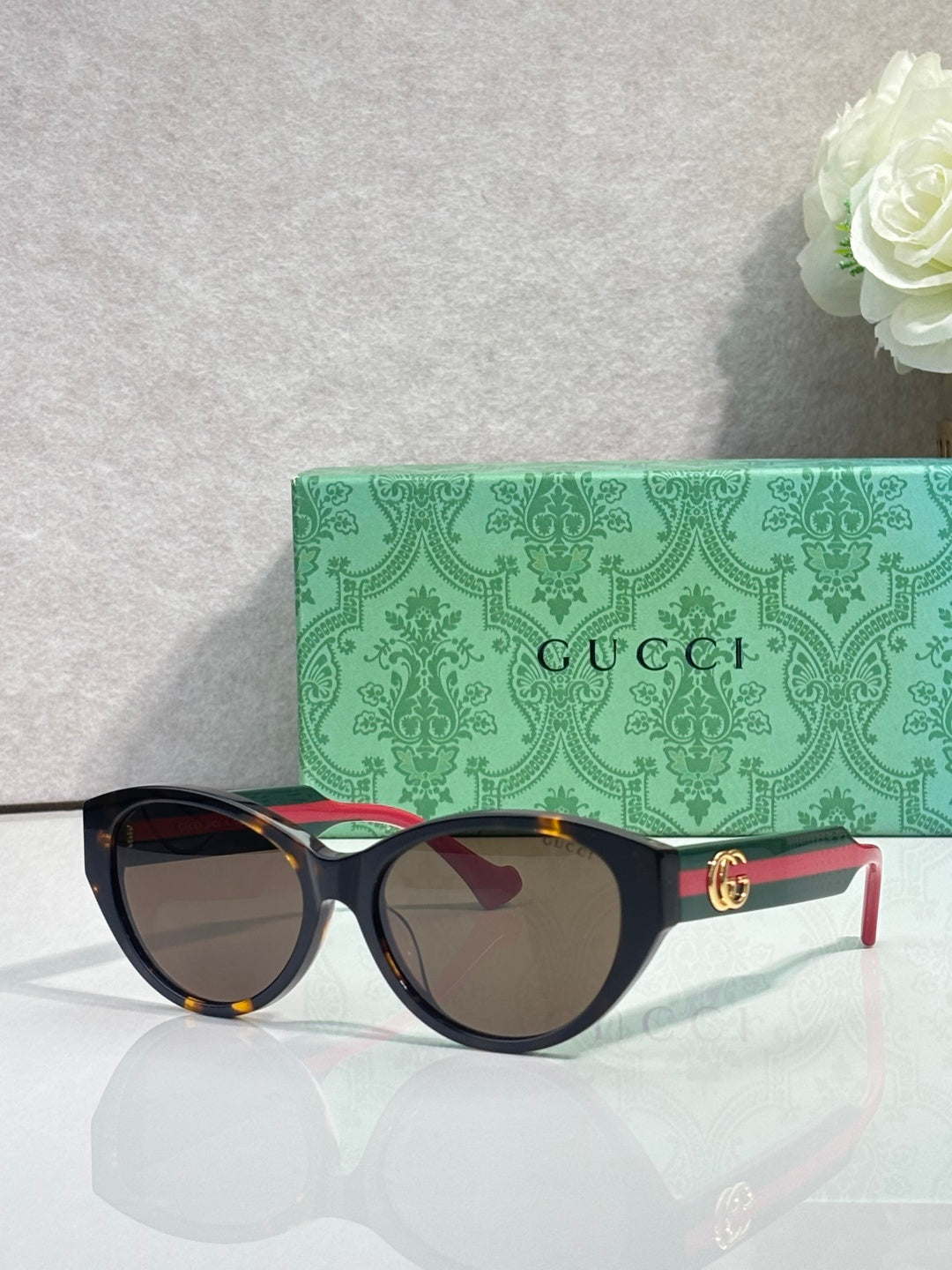 Gucci eyeglasses with dark tortoise frame and gold emblem on temple, tinted lenses.