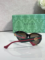 Gucci eyeglasses with black frame, green accents, and red temple tips, tinted lenses.