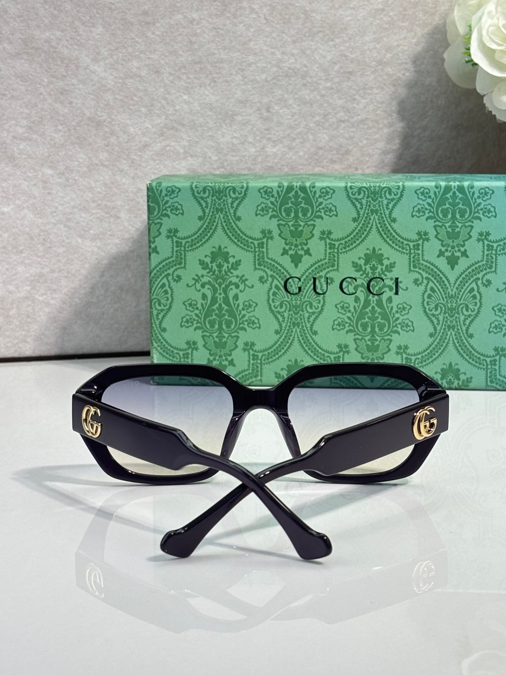 Gucci square sunglasses with dark frame, dark tinted lenses, and gold logo temples