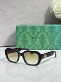 Gucci square sunglasses with dark frame, lightly tinted lenses, and gold logo temples