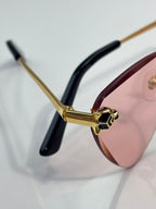 Cartier gold eyeglasses hinge detail with black temple tips and pink lenses, close-up
