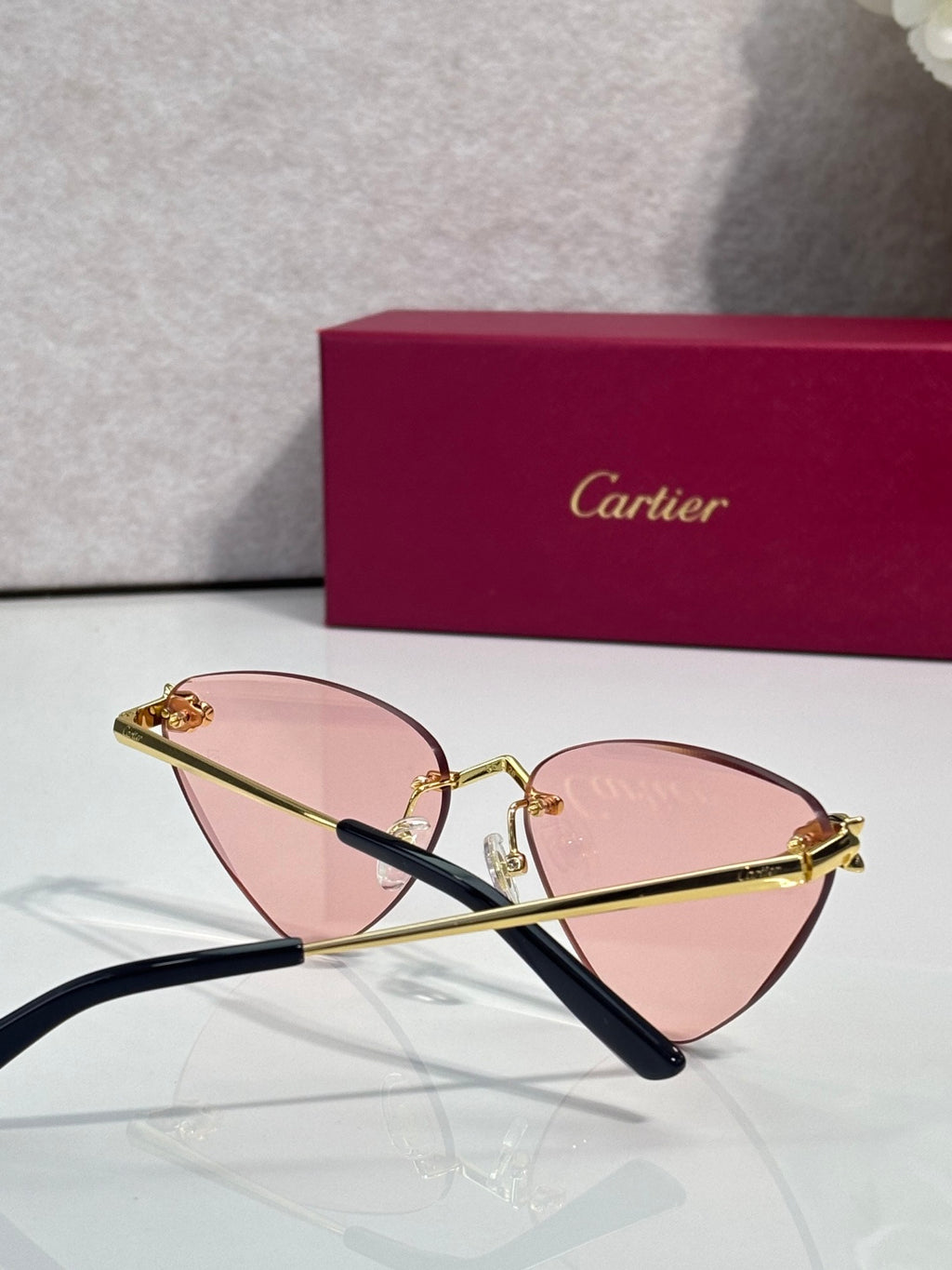 Cartier gold eyeglasses with black temples and pink-tinted lenses, front view