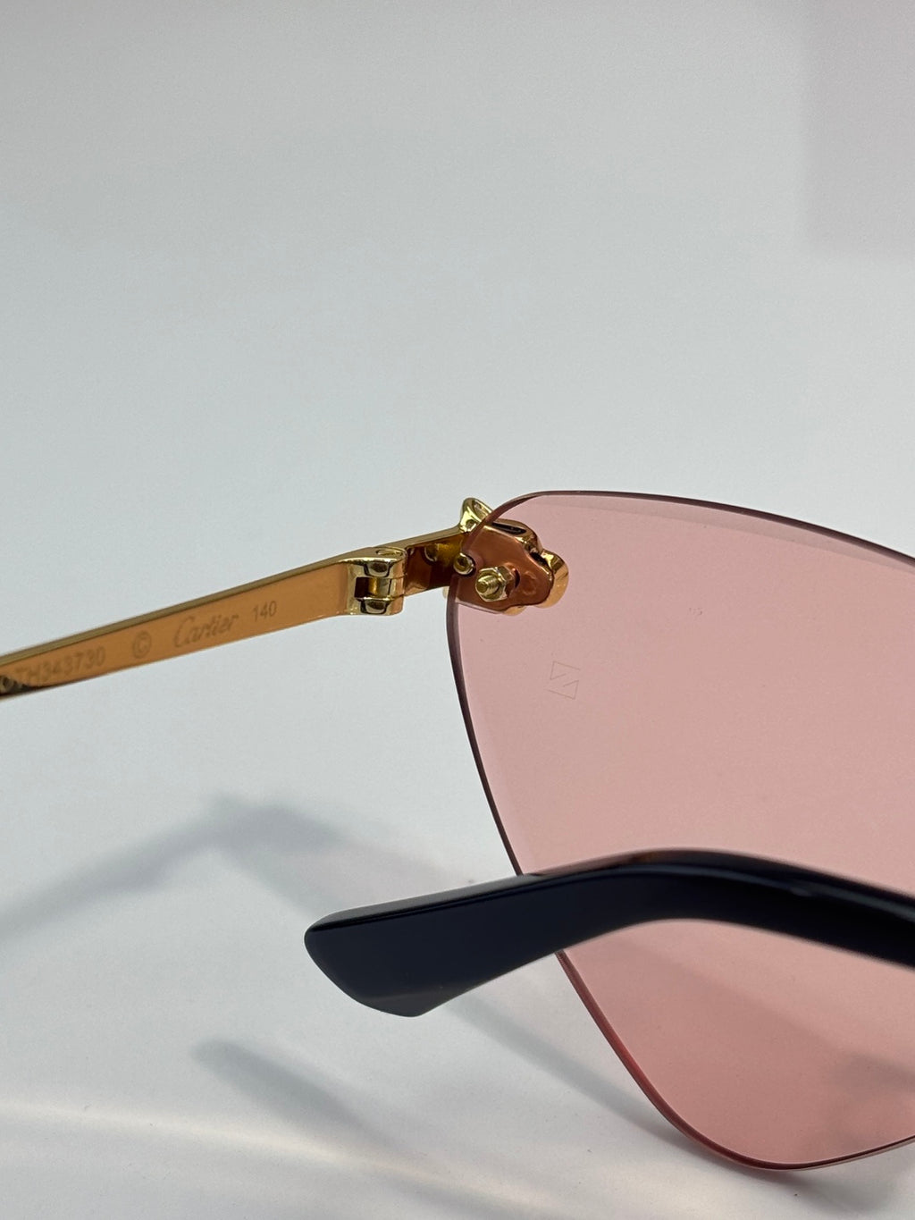 Cartier gold eyeglasses with black temple tips and pink-tinted lenses, side view