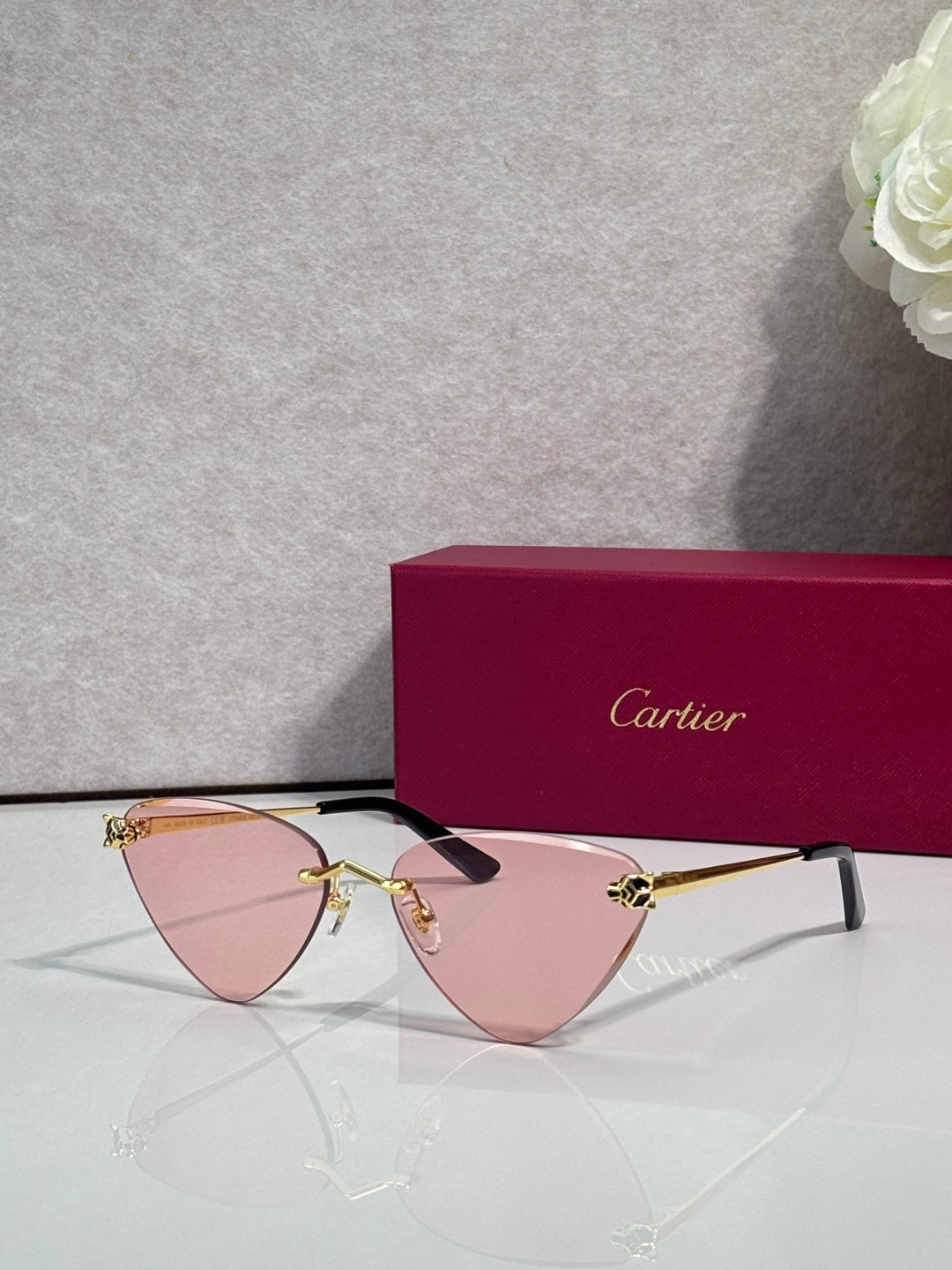 Cartier gold metal eyeglasses with black temples, pink-tinted lenses, cat-eye style