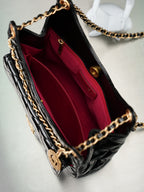 Chanel bag open to burgundy interior lining and inner pocket, black quilted exterior