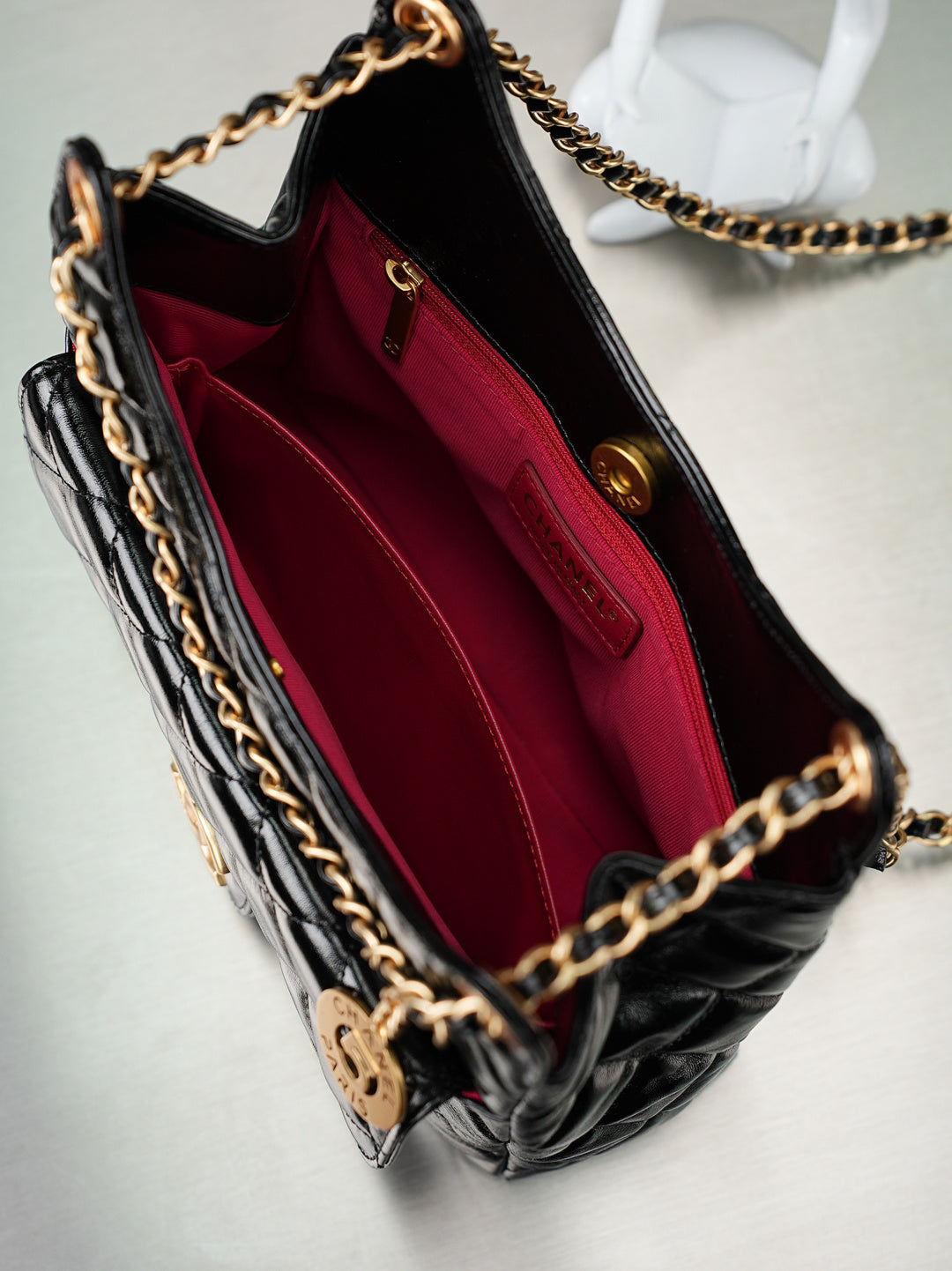 Chanel bag open to burgundy interior lining and inner pocket, black quilted exterior