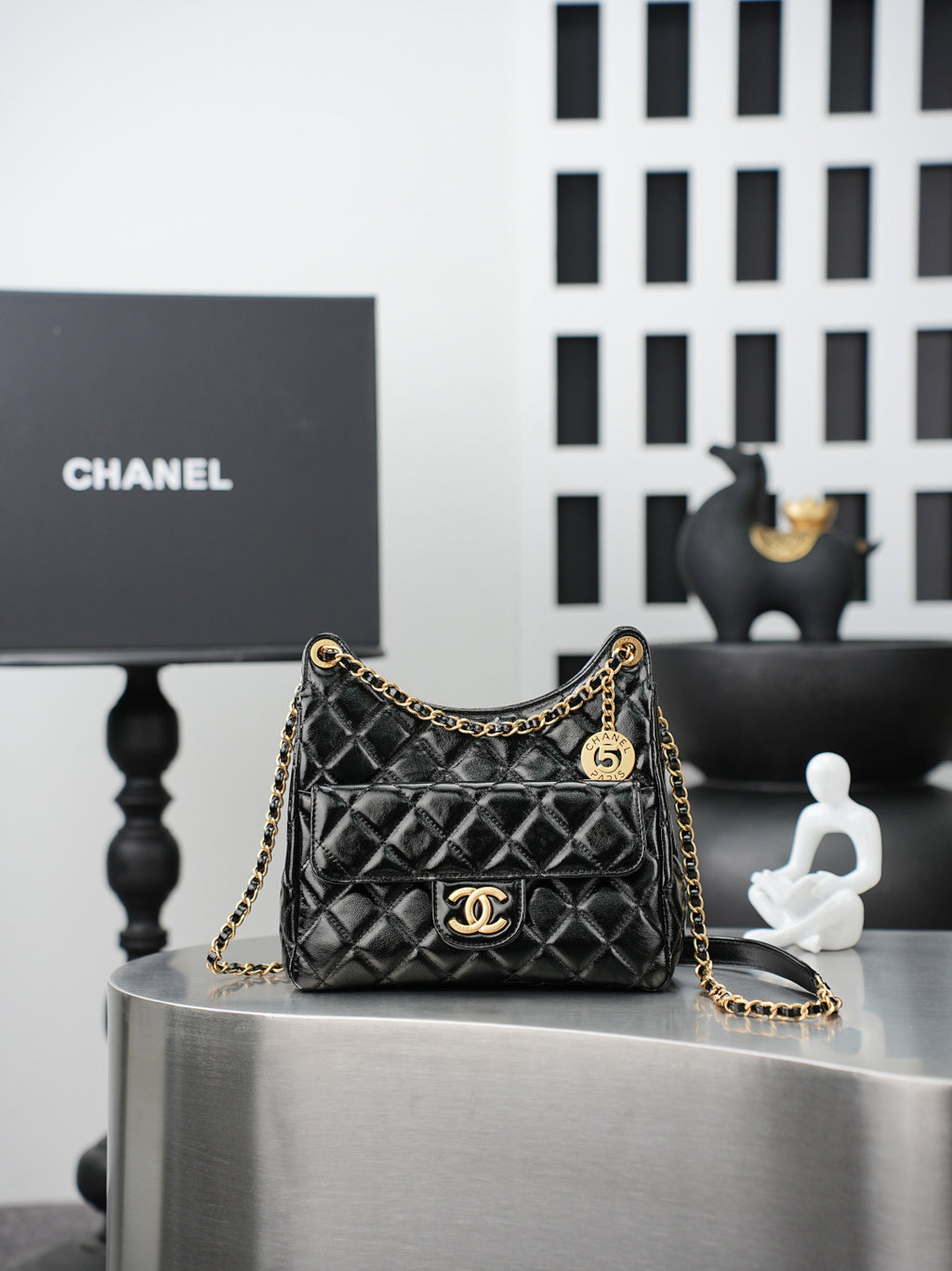 Quilted Chanel bag with gold chain strap and curved top handle, black leather finish