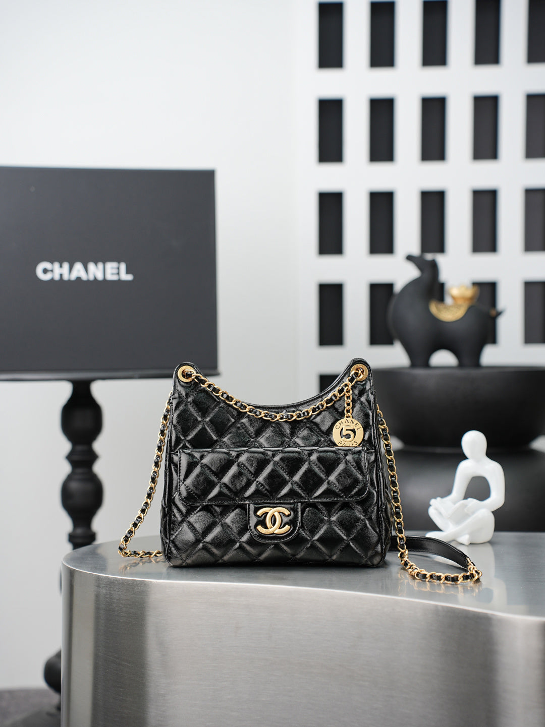 Quilted Chanel bag with gold chain strap and curved top handle, black leather finish
