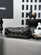 Quilted Chanel bag laid flat, black leather with gold chain strap detail