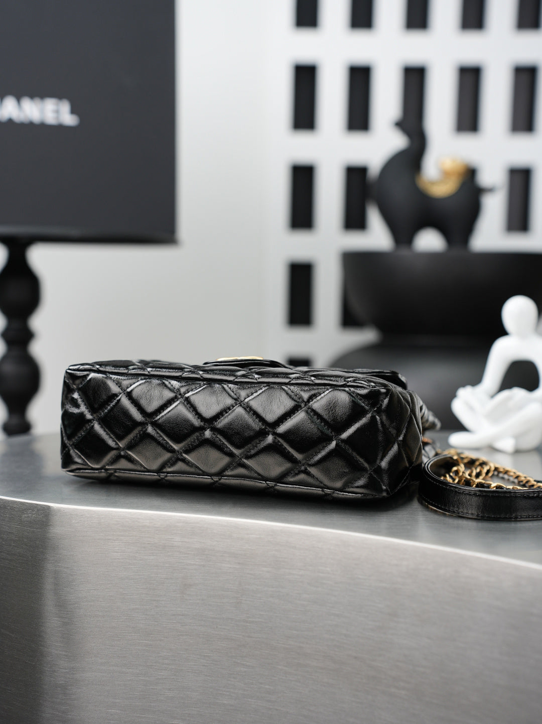 Quilted Chanel bag laid flat, black leather with gold chain strap detail