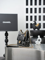 Quilted Chanel bag with gold chain strap, small top handle, black leather exterior