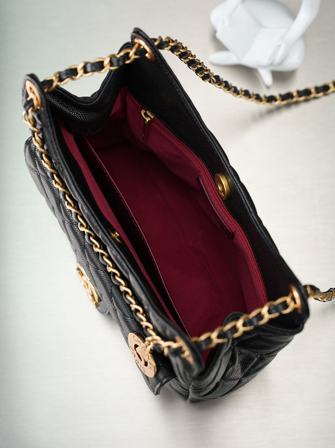 Chanel bag interior with burgundy lining, open top, and gold chain trim