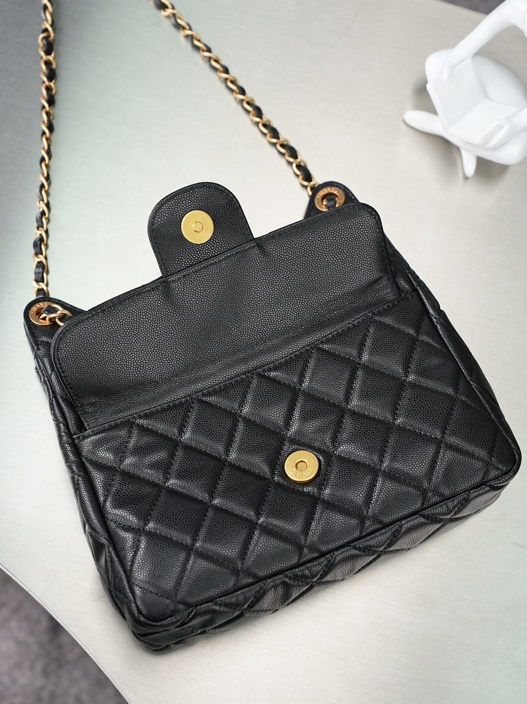 Chanel quilted handbag with gold chain strap and flap closure in dark color