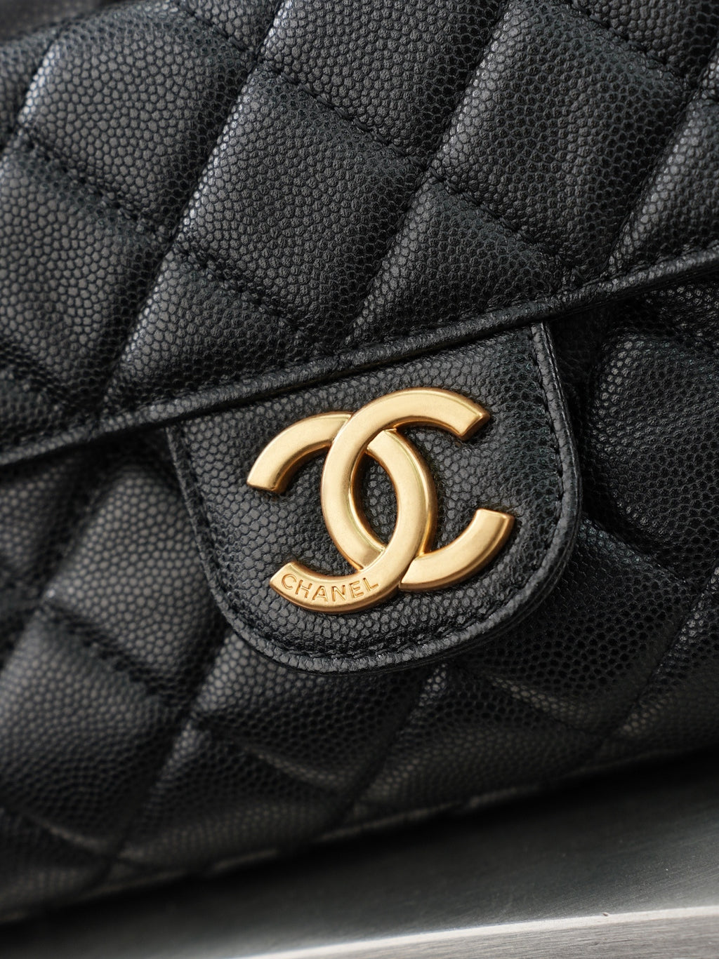 Chanel CC logo on quilted dark leather bag front with gold-tone emblem
