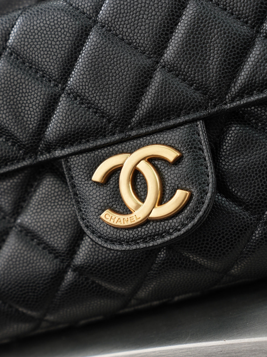 Chanel CC logo on quilted dark leather bag front with gold-tone emblem