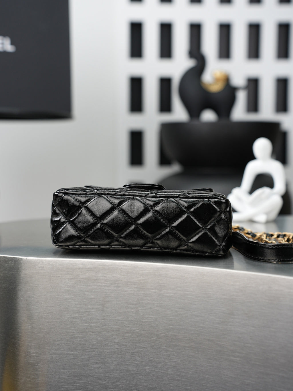 Chanel quilted black flap bag with gold chain handle, shown from the side