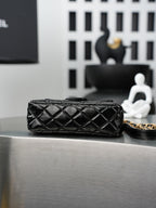 Chanel quilted black flap bag with gold chain handle, shown from the side