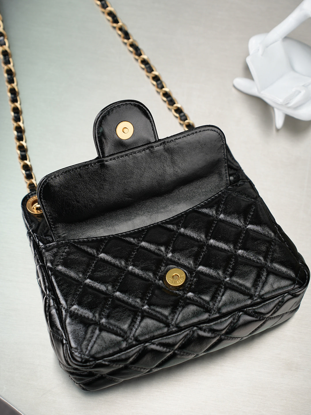 Chanel quilted black bag open with red interior and gold-tone button closure