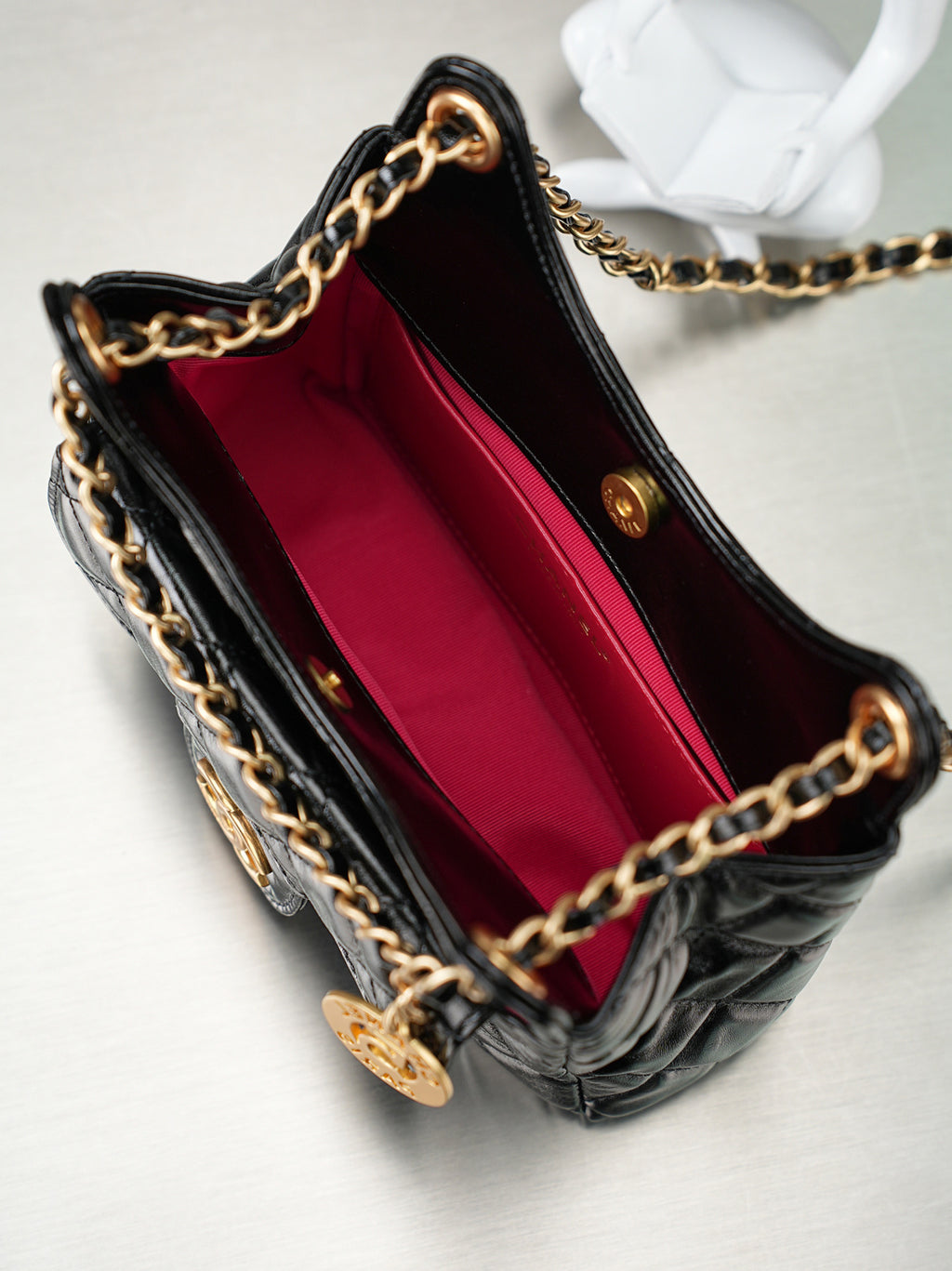 Chanel quilted black bag open to red lining with gold chain strap