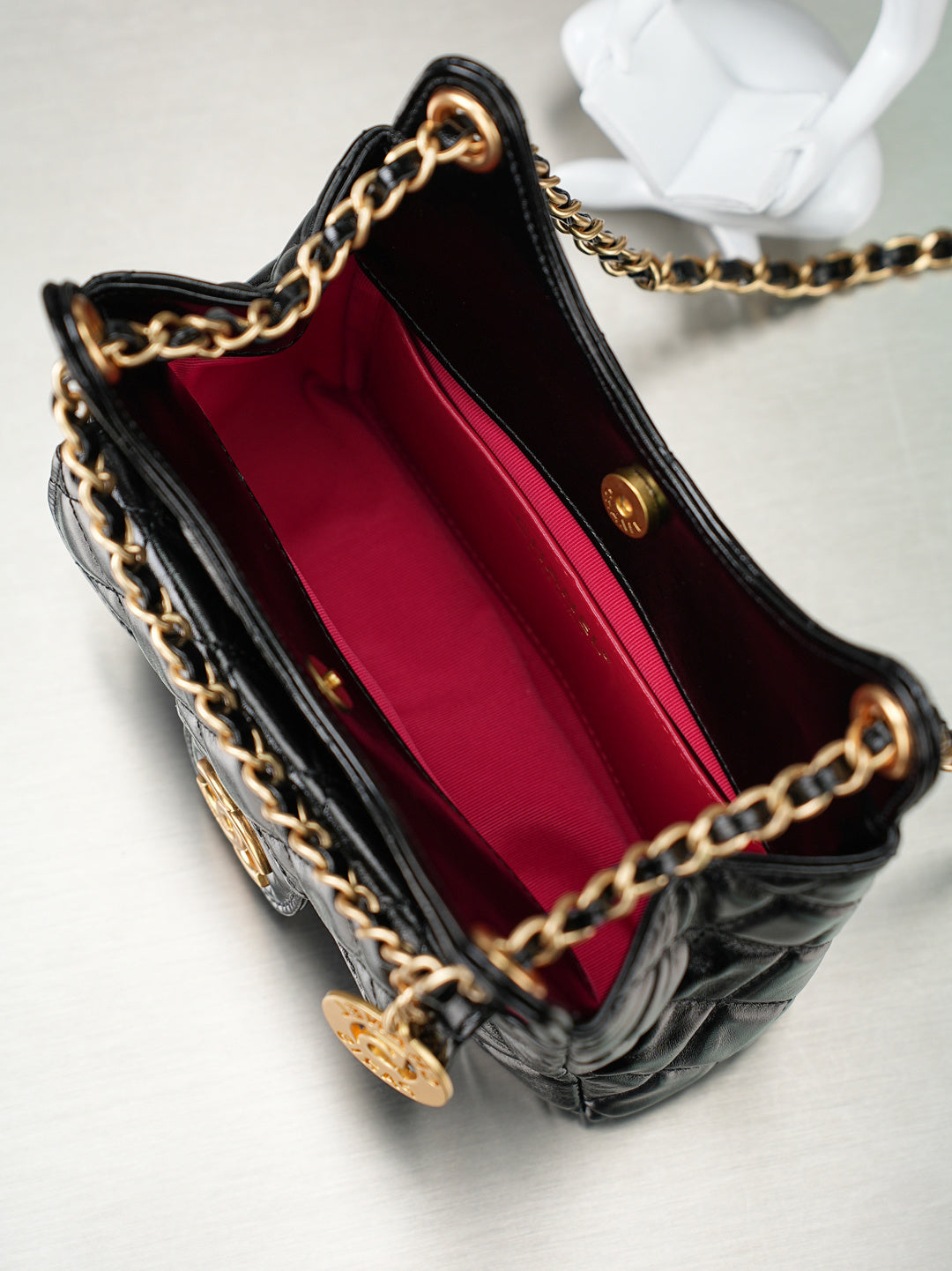 Chanel quilted black bag open to red lining with gold chain strap