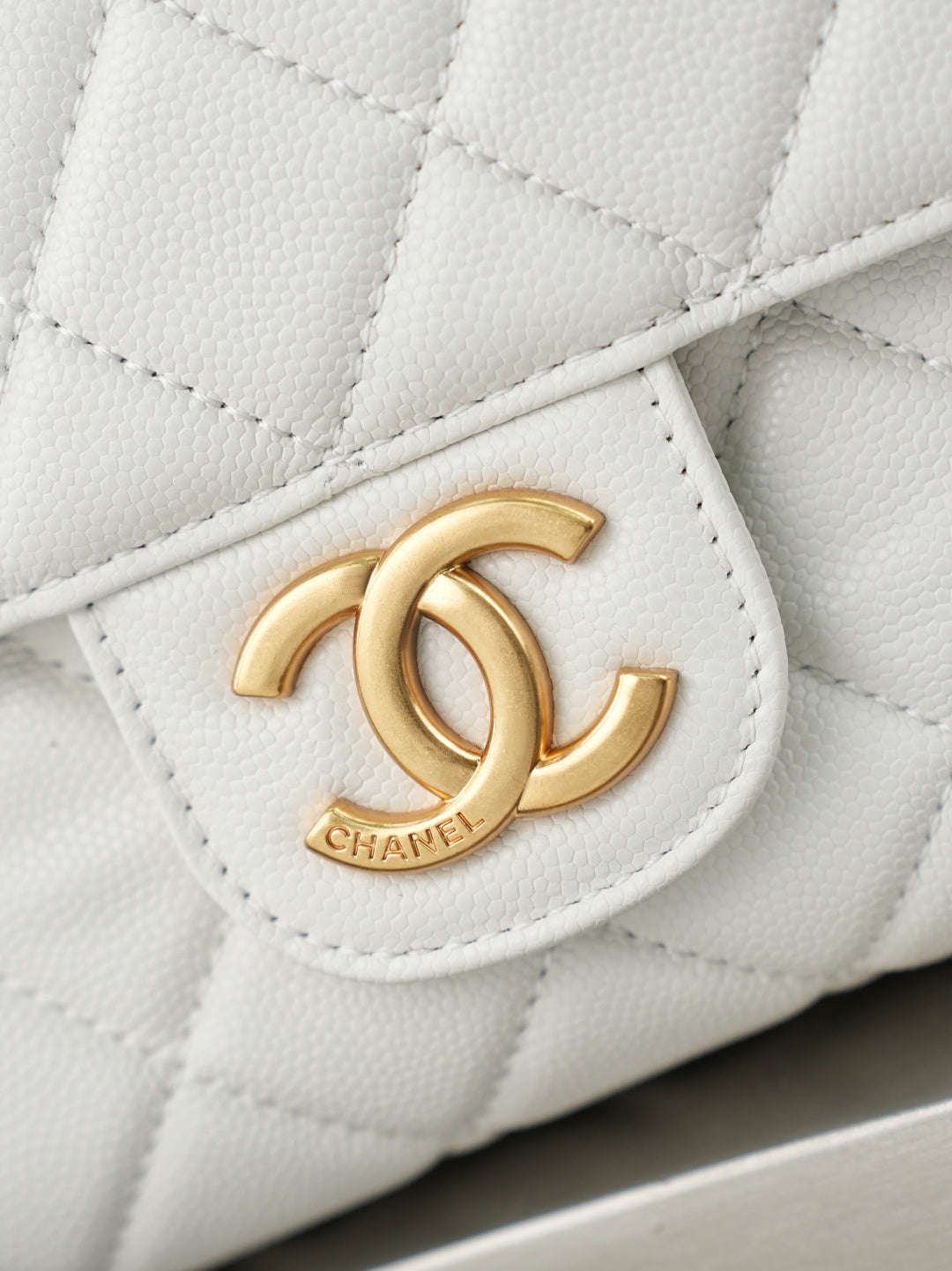 Chanel CC logo medallion on a white quilted flap with gold hardware