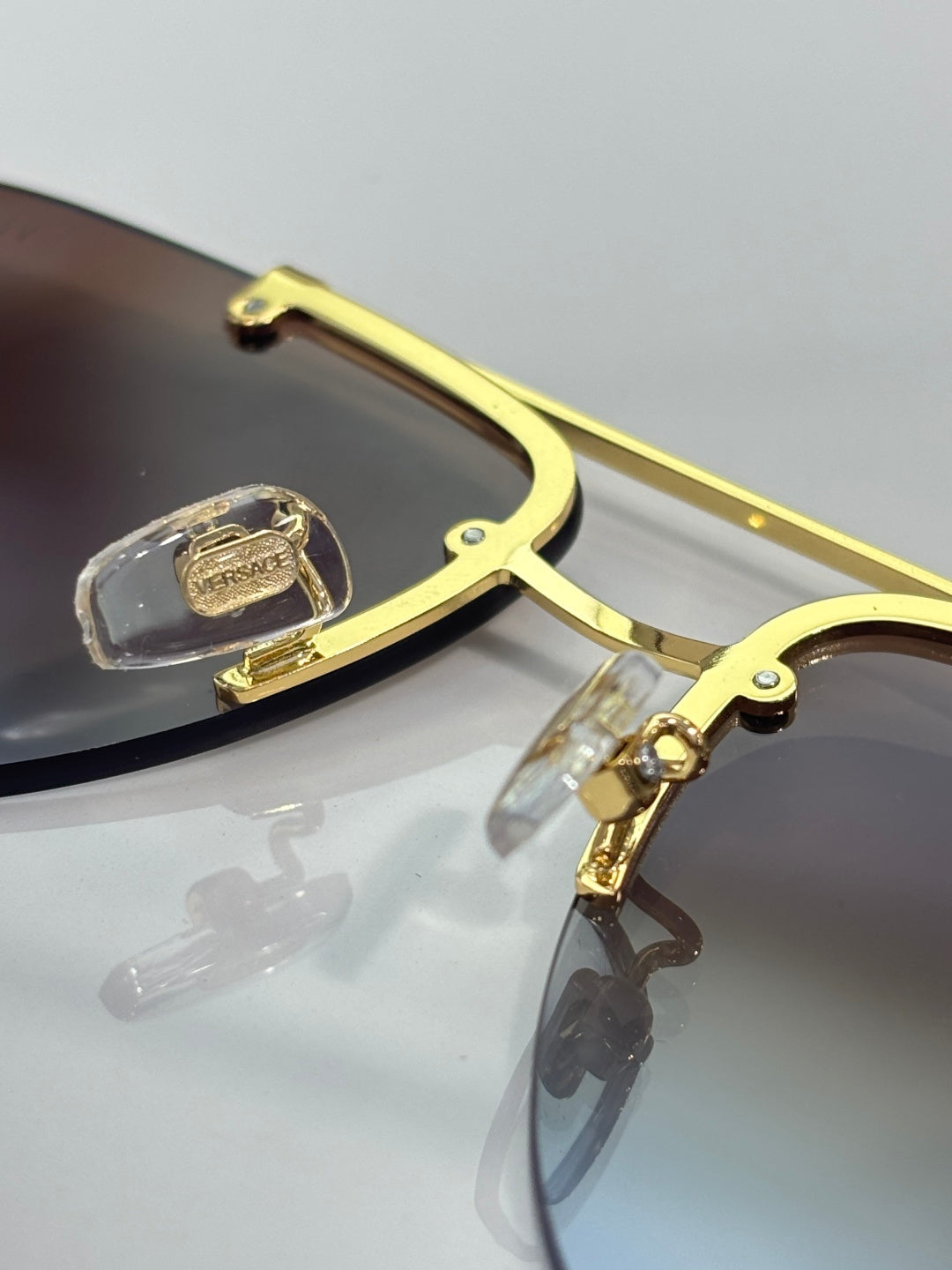 Versace pilot sunglasses close-up, gold-tone temple with logo detail