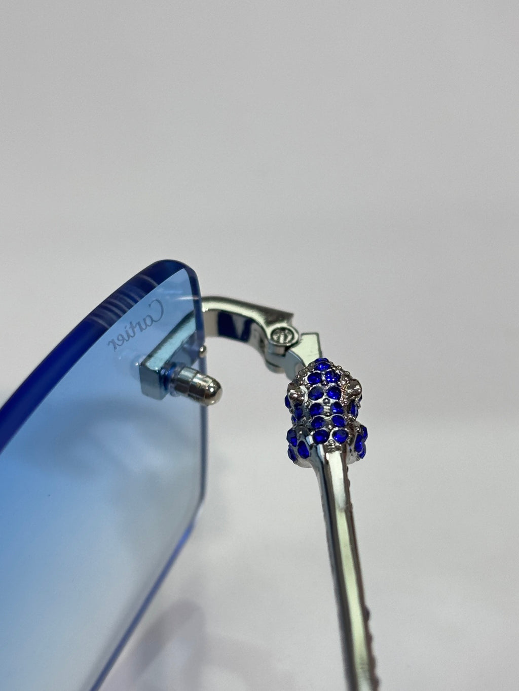 Cartier eyeglass temple detail with blue rhinestone cluster on metal frame.