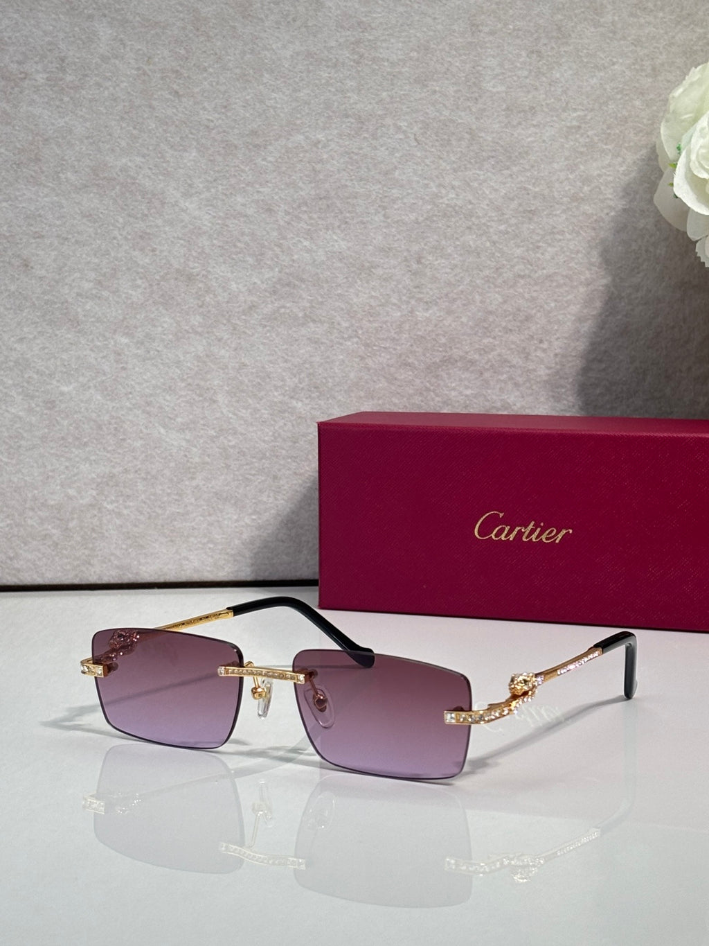 Cartier eyeglasses with purple-tinted lenses, gold frame, and blue crystal accents.
