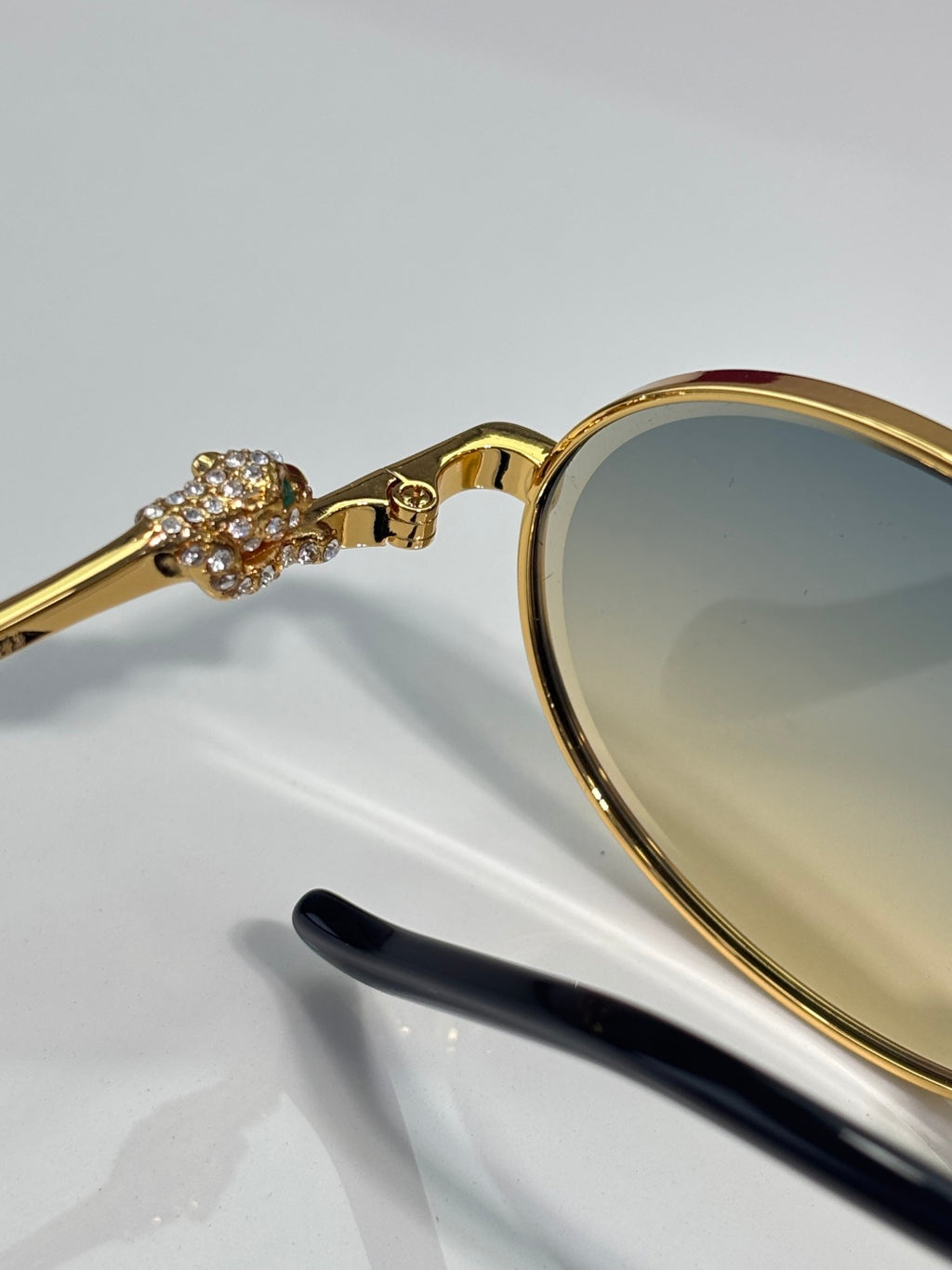 Gold-tone round sunglasses close-up: rhinestone ornament on temple