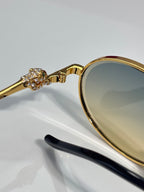 Gold-tone round sunglasses close-up: rhinestone ornament on temple