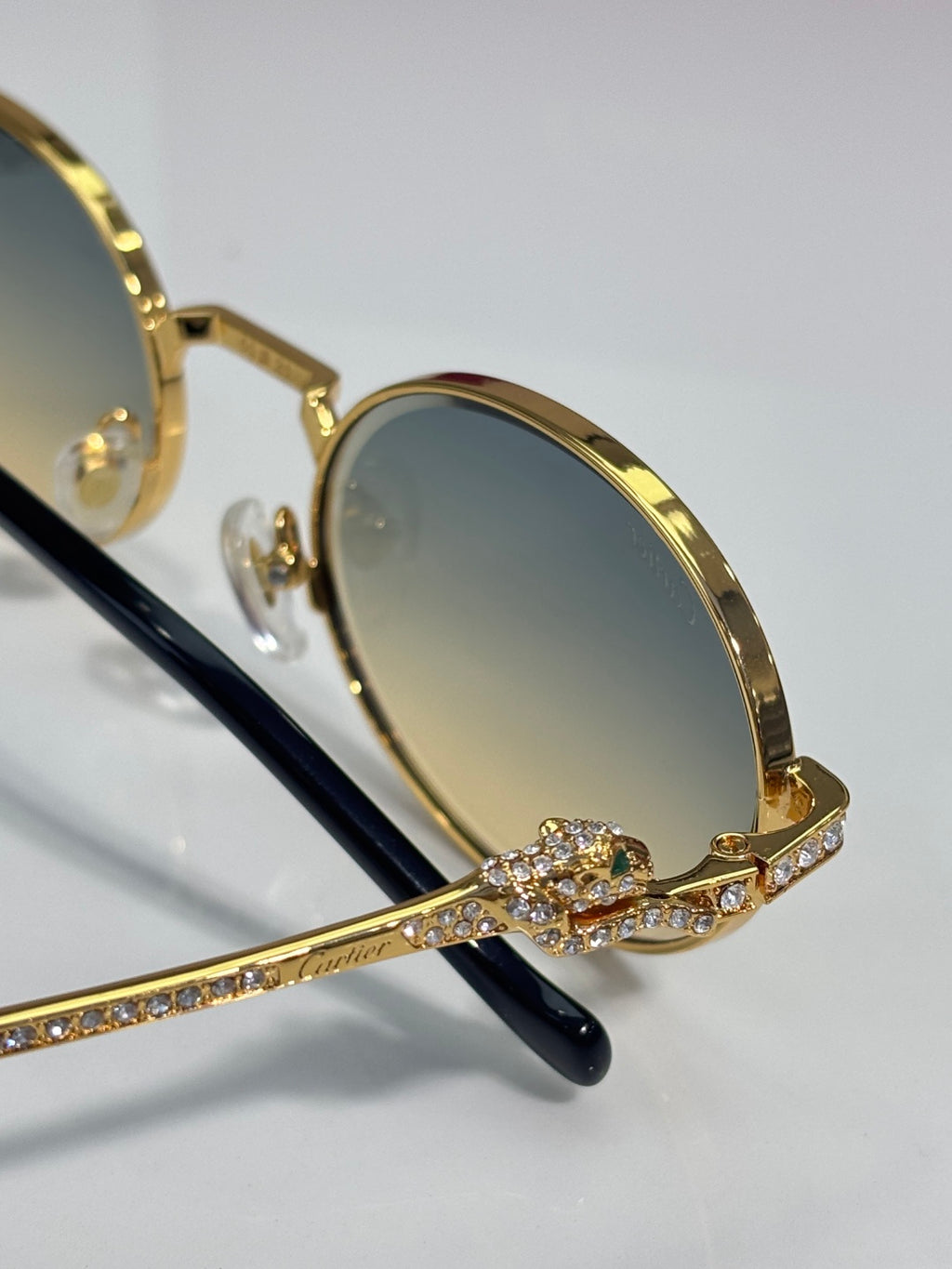 Cartier round eyeglasses close-up: gold frame with rhinestone detail and black temple