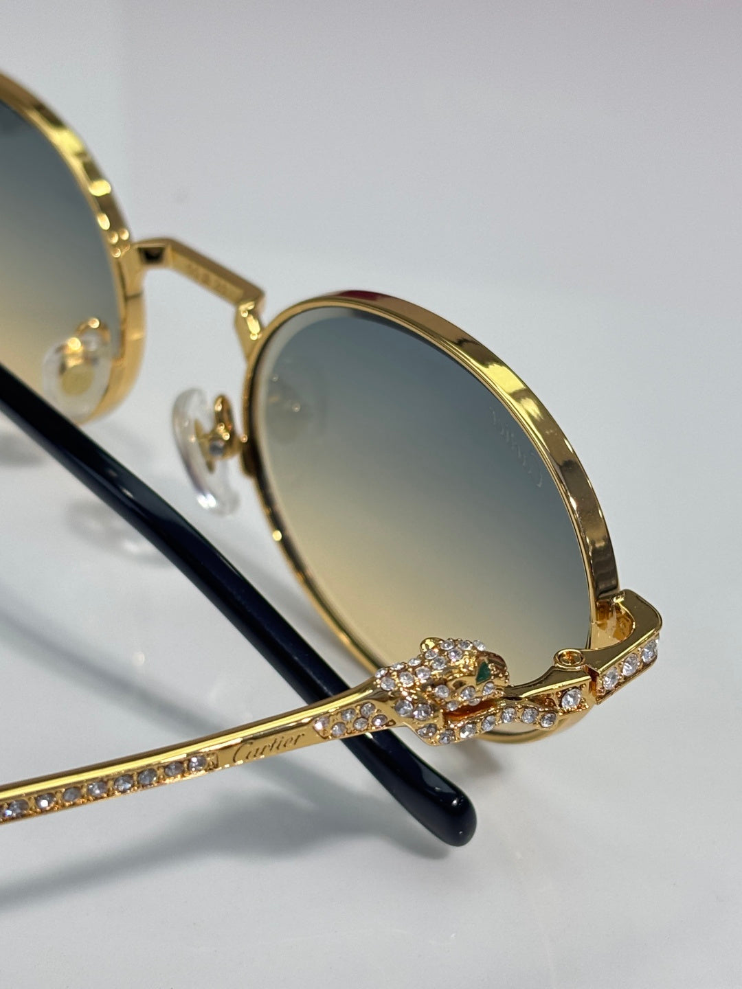 Cartier round eyeglasses close-up: gold frame with rhinestone detail and black temple