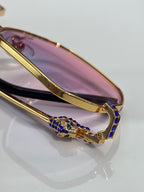 Cartier eyeglasses bridge detail with gold frame and blue jeweled accents.