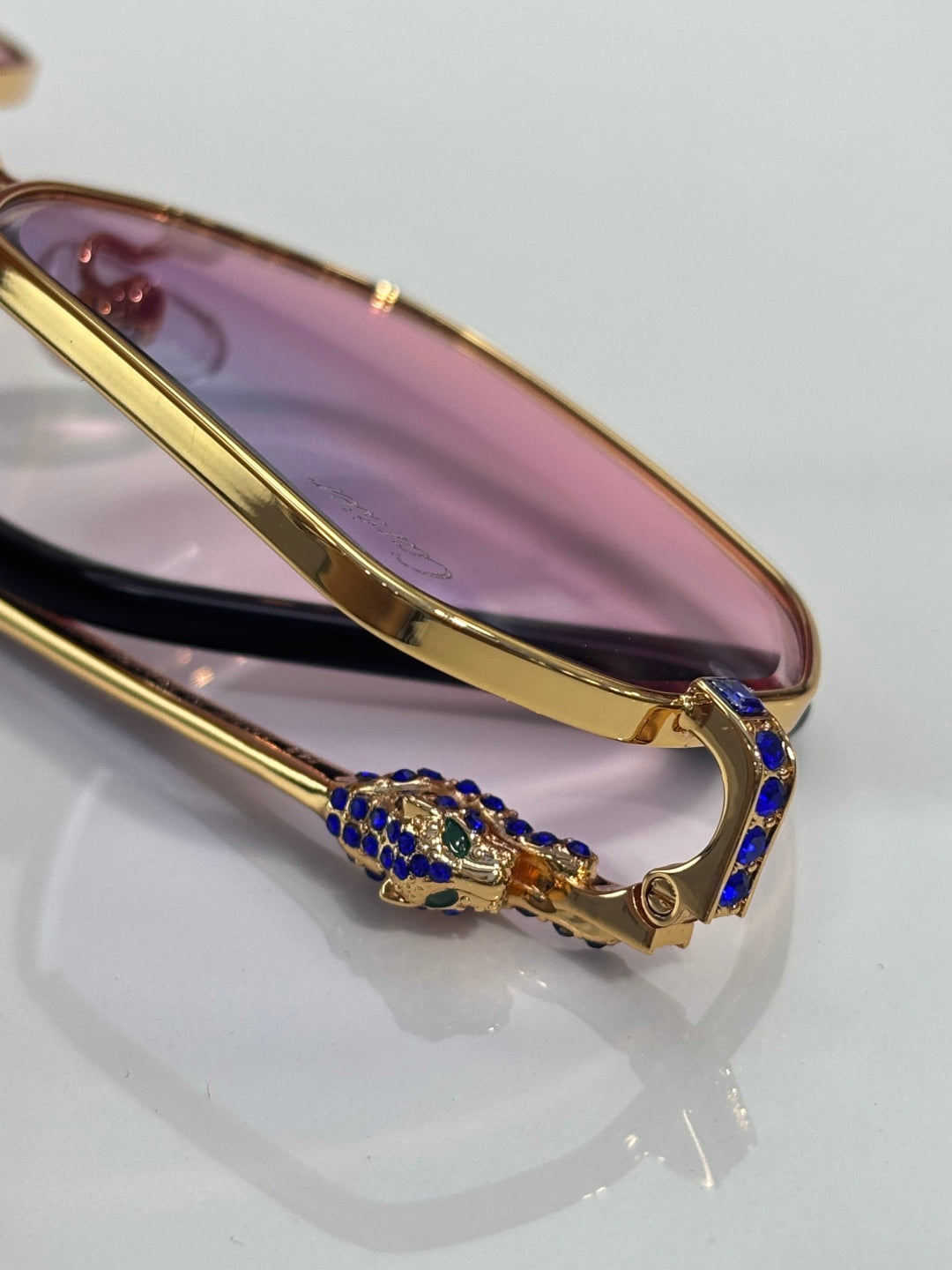 Cartier eyeglasses bridge detail with gold frame and blue jeweled accents.