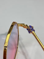 Cartier eyeglasses side arm with gold finish and blue jeweled emblem detail.