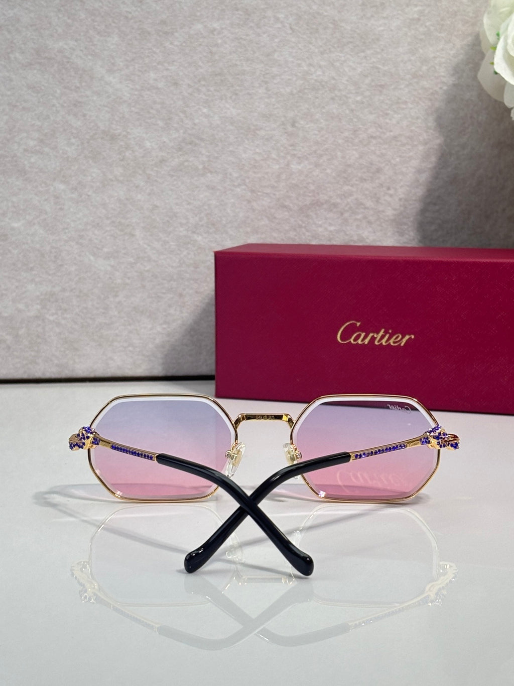 Cartier eyeglasses with rose-pink lenses and light gold frames, black temple arms.