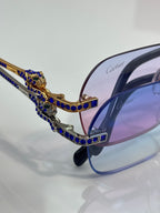 Cartier eyeglasses close-up: blue-and-gold frame with jeweled crest and Cartier logo on lens