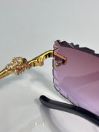 Gold eyeglass frame with pink lens and diamond-like floral ornament on temple