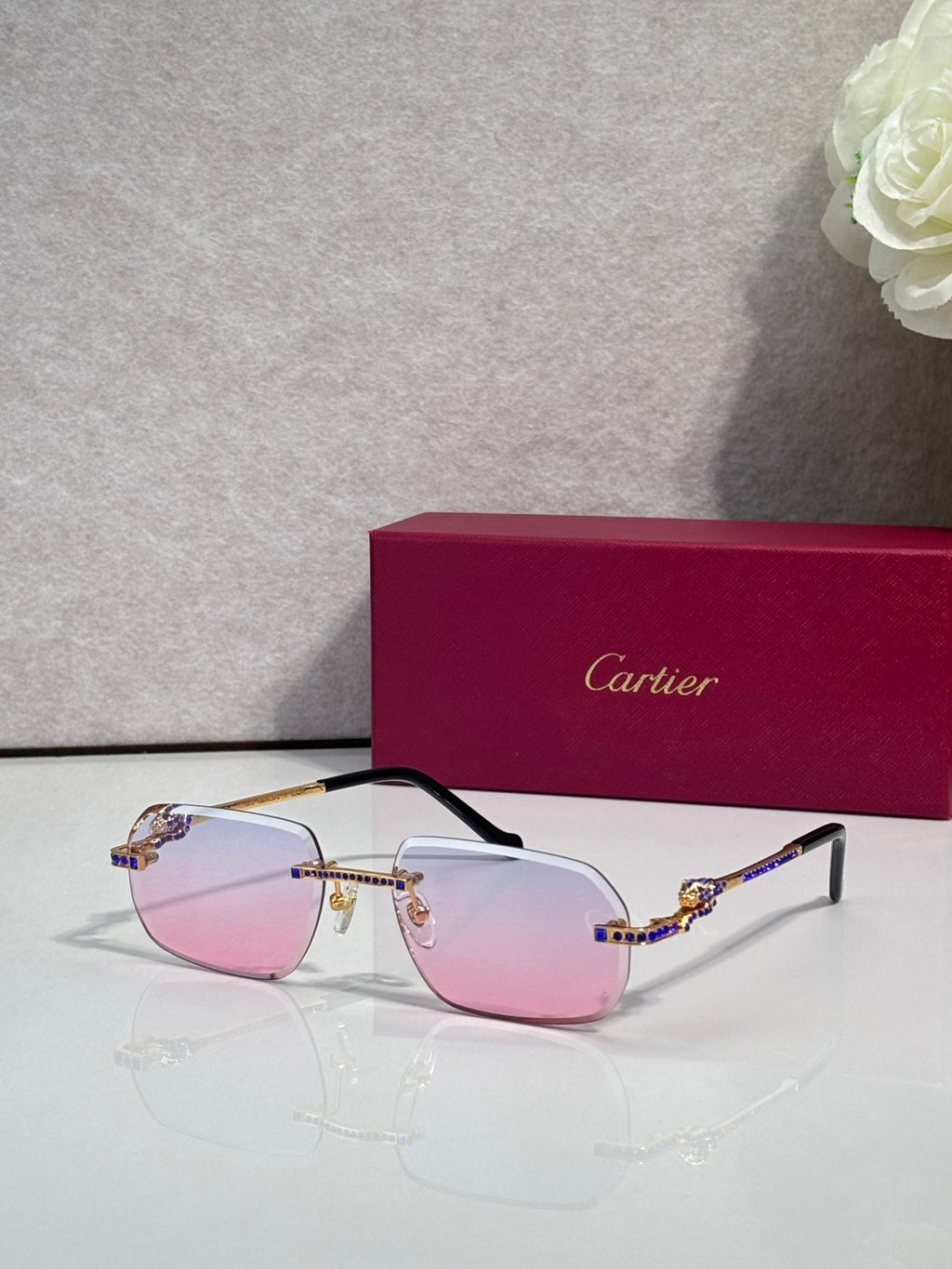 Cartier eyeglasses with gold frame and pale pink lenses, blue gem accents