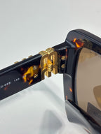 MiuMiu sunglasses hinge close-up with gold hardware and tortoiseshell arm