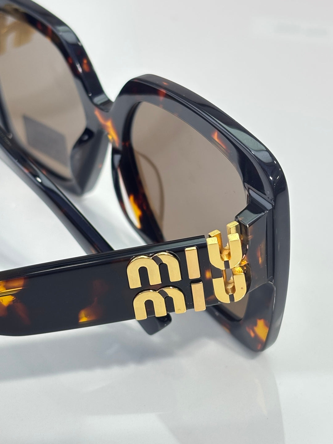 MiuMiu sunglasses temple with gold 'miu miu' logo on tortoiseshell frame