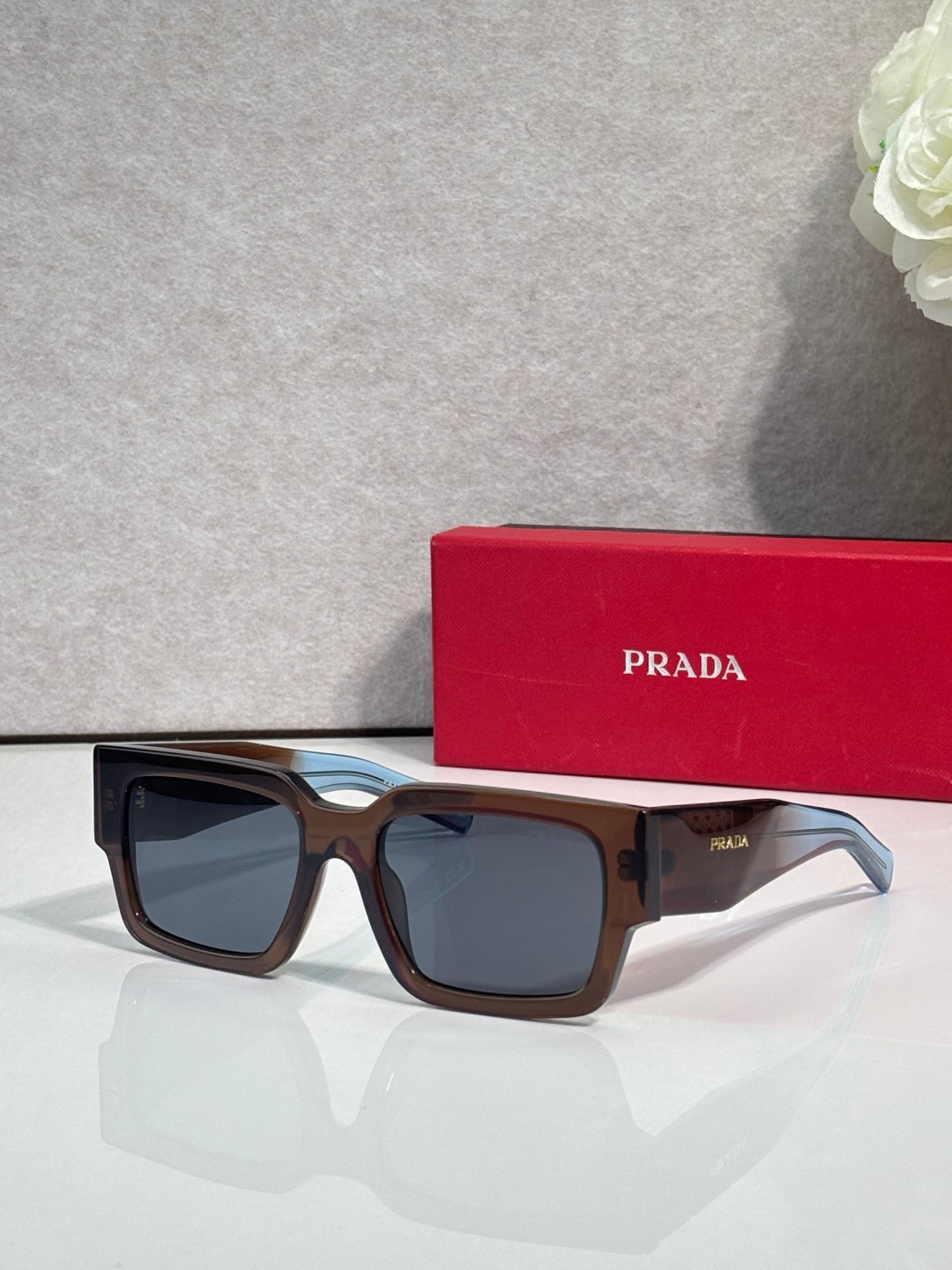 Brown and black sunglasses with dark lenses and Prada logo on temple