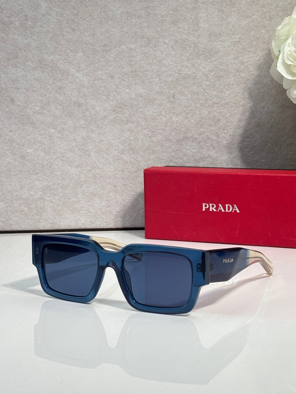 Blue and black sunglasses with dark lenses and Prada logo on temple